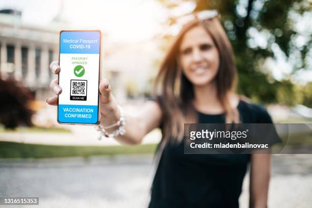 jonge vrouw die een digitaal vaccincertificaat op haar smartphone toont - geven stockfoto's en -beelden