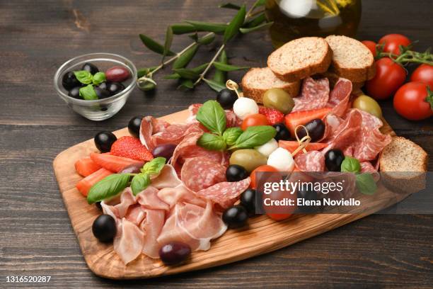 charcuterie board salami, prosciutto, with green and black olives, appetizers with mozzarella balls, cherry tomatoes and strawberries. - charcuterie board 個照片及圖片檔