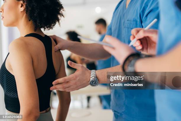 african american woman sitting on the bad having physical examination - spinal column stock pictures, royalty-free photos & images