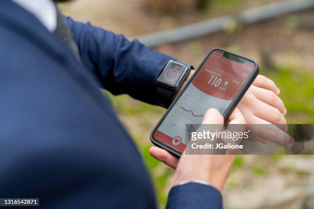 geschäftsmann unterwegs überprüfen seinen glukosespiegel mit einer smartwatch und telefon-app - traubenzucker stock-fotos und bilder
