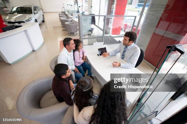 salesman at the dealership talking to a family buying a car - car dealership stock pictures, royalty-free photos & images