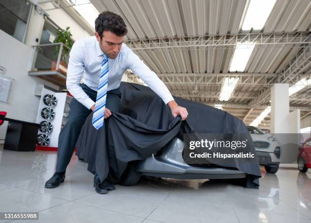 salesman disclosing a car covered with tarpaulin at the dealership - car launch event stock pictures, royalty-free photos & images
