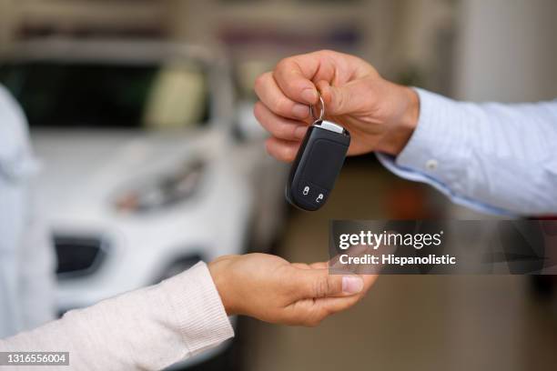 close-up op een verkoper die de sleutels van hun nieuwe auto aan een paar bij de handelaar geeft - car rental stockfoto's en -beelden