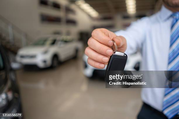 verkäufer hält die schlüssel eines neuwagens im autohaus - auto mieten stock-fotos und bilder