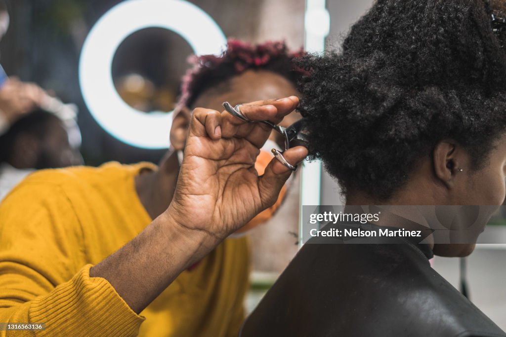 Close-up of a black hairstylist cutting a black woman's afro hair