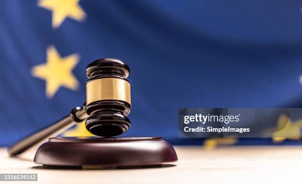 a wooden judge gavel with flag of european union in the background. - sentencing fotografías e imágenes de stock