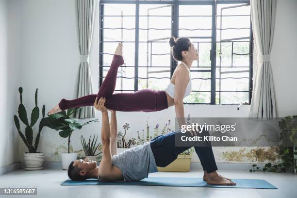 couple practicing acro yoga in a yoga studio - couple doing yoga stock pictures, royalty-free photos & images