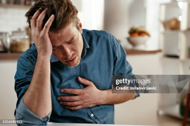 retrato do homem colocando as mãos no peito sofrendo de dor no coração. - symptom - fotografias e filmes do acervo