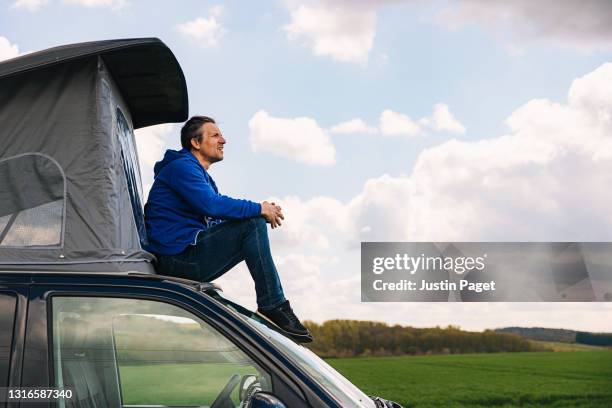 man looking at the view from the roof of his campervan - caravan uk stock pictures, royalty-free photos & images