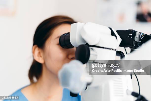 aziatische tandarts die tanden met moderne apparatuur in kliniek onderzoekt. - wortelkanaal stockfoto's en -beelden