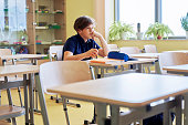 Boy sitting alone in empty classroom