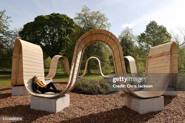 Woman enjoys the sunshine as she lies on the installation 'Please be seated' by Paul Cocksedge Studio, part of The 'Secret World Of Plants' at Kew...