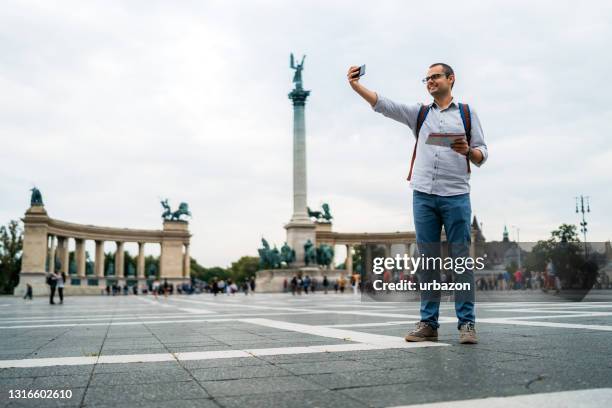 young male tourist making selfie on heroes square - budapest map stock pictures, royalty-free photos & images