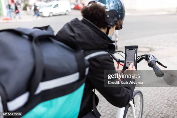 delivery man accepting new food delivery ride on phone - take away food courier stock pictures, royalty-free photos & images