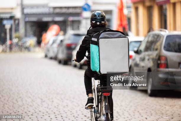 delivery person with thermal box on a bicycle in town - livre photos et images de collection