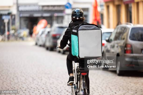 delivery person with thermal box on a bicycle in town - 宅配便サービス ストックフォトと画像