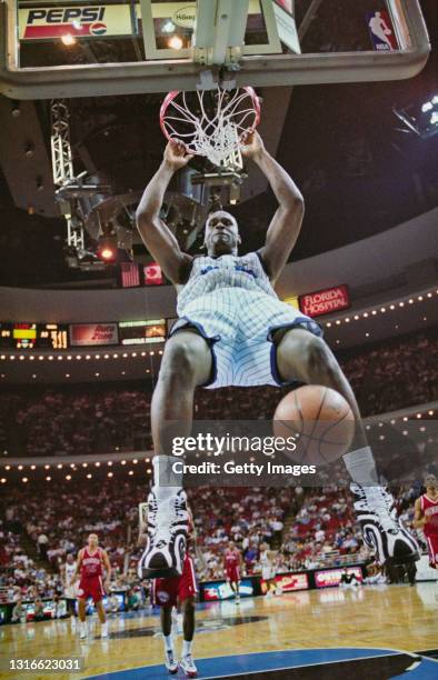 Shaquille O'Neal, Center for the Orlando Magic hangs off the the rim following a slam dunk score during the NBA Atlantic Division basketball game...