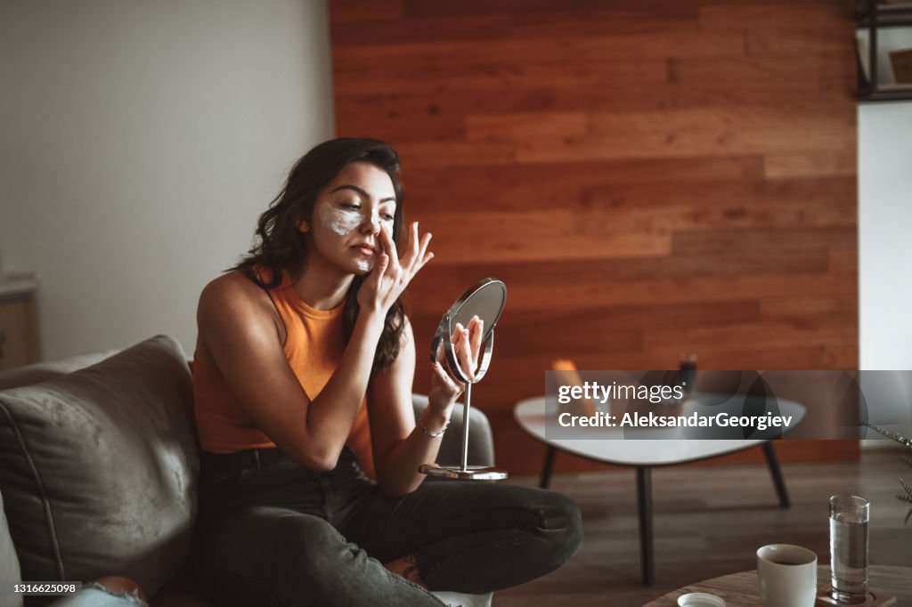 Modern Female Caring About Facial Skin And Applying Moisturizer In Mirror