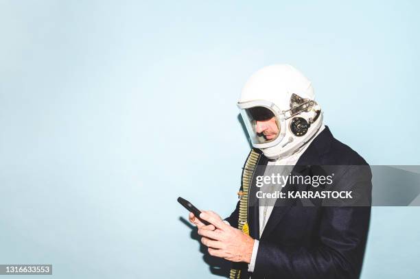 businessman with astronaut helmet using smart phone - protection humour stock-fotos und bilder