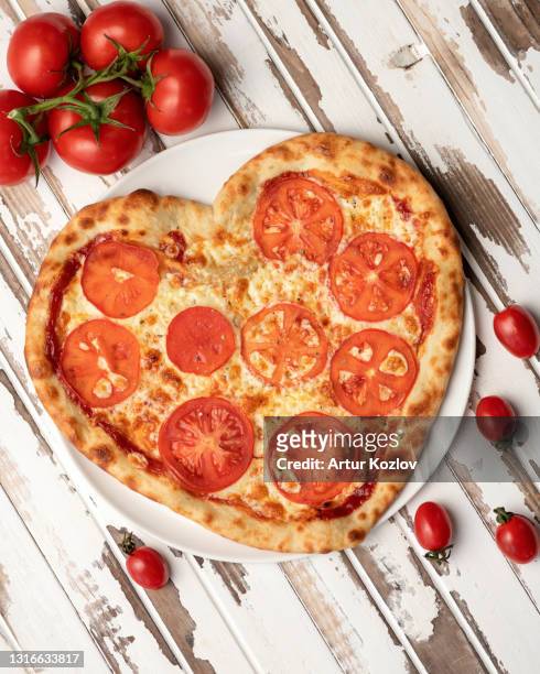 romantic heart shaped pizza with tomato slices on white wooden table background. top view. valentine day concept. delicious pizza. traditional italian food. nutrition dinner or lunch - heart shape pizza stock pictures, royalty-free photos & images