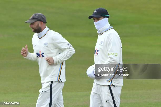 Yorkshire fielder Tom Kohler-Cadmore keeps his hands warm whilst wearing a face covering as team mate Adam Lyth looks on during day one of the LV=...