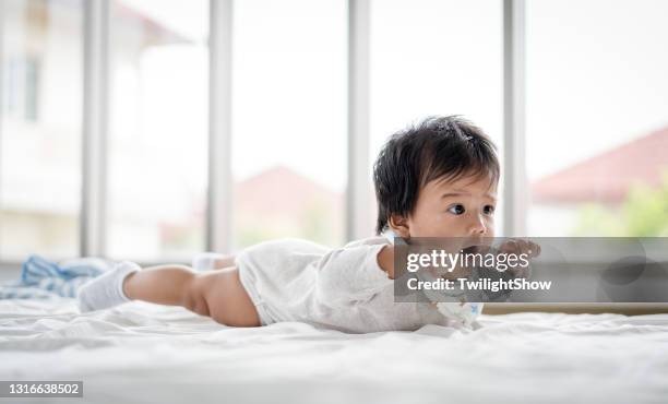 chéri asiatique jouant avec à la maison - allongé sur le devant photos et images de collection