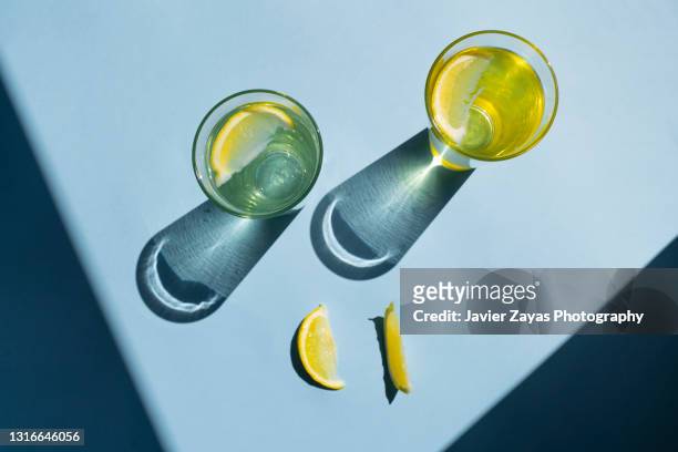 fresh homemade lemonade glasses on blue colored background - sunlight through drink glass stock-fotos und bilder