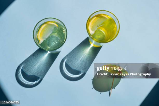 fresh homemade lemonade glasses on blue colored background - cocktail umbrella stock pictures, royalty-free photos & images