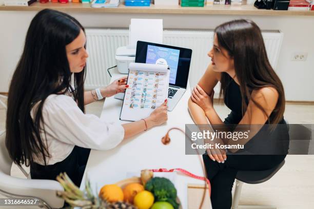 彼女の近代的なオフィスでの相談の間に、彼女の患者に、新しいダイエット体制を提示する専門知識を持つ女性栄養学 - high fibre diet ストックフォトと画像