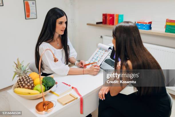 respectable female nutritionist and dietologist, explaining the new dieting meal plan to her young female patient - high fibre diet stock pictures, royalty-free photos & images