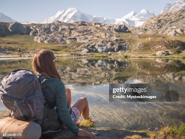 female hiker relaxes on meadow near alpine lake - bivouac stock pictures, royalty-free photos & images