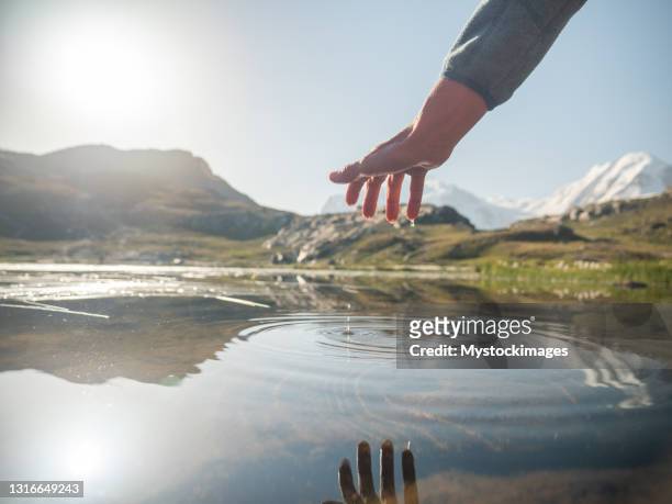 dettaglio dell'acqua che tocca a mano nel lago di montagna sotto il ghiacciaio - cantòn vallese foto e immagini stock