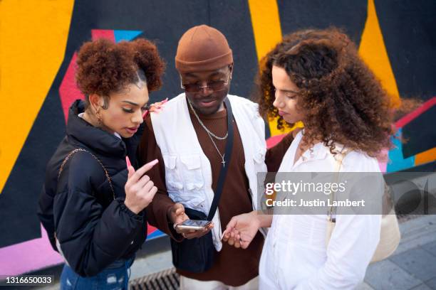 friends sharing photos together on their phones against a bright backdrop - mensagem com foto imagens e fotografias de stock
