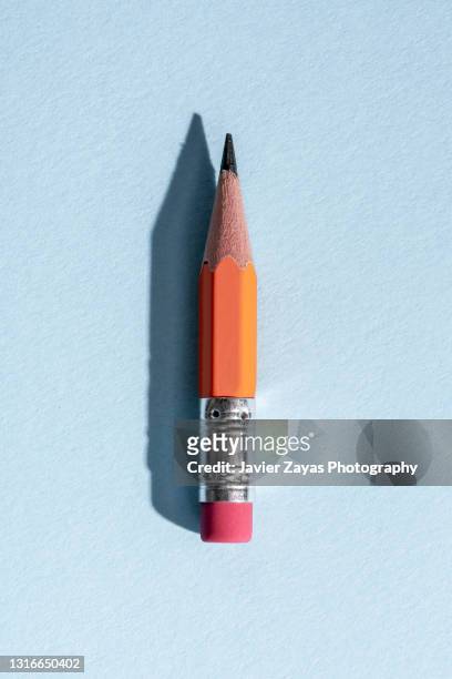 used worn orange pencil with eraser on blue background - pencil stock pictures, royalty-free photos & images