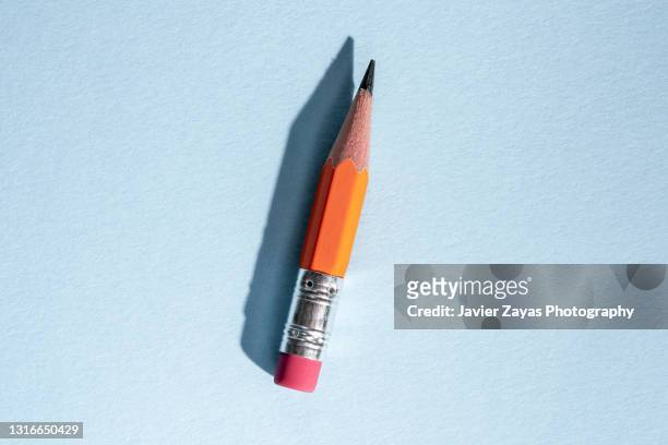 used worn orange pencil with eraser on blue background - writing instrument bildbanksfoton och bilder