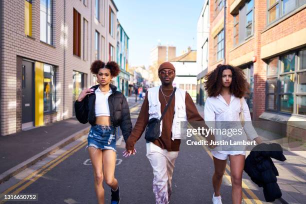 friends confidently walking along a city street in bright sunlight - fashion stock pictures, royalty-free photos & images