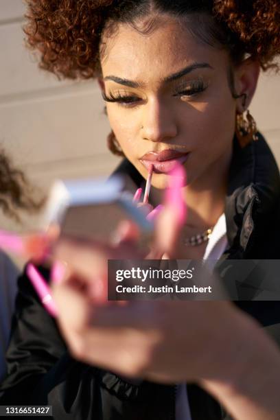 trans woman applying lip gloss in a mirror - lipstick mirror stock pictures, royalty-free photos & images
