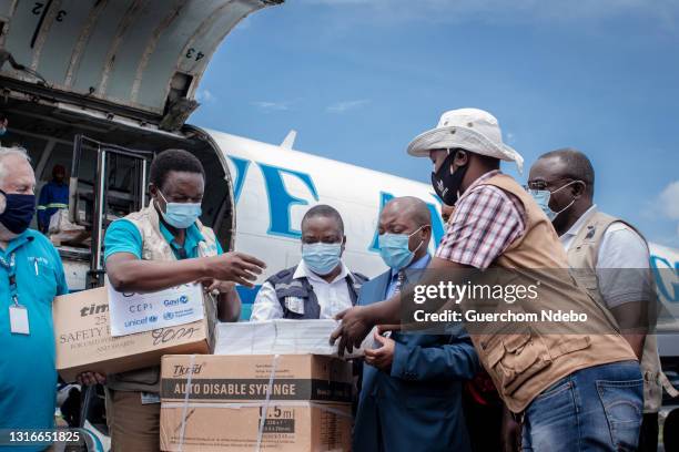 Airport staff and health personnel handle containers containing doses of AstraZenica Covid-19 vaccine during the arrival of a new batch at Goma...