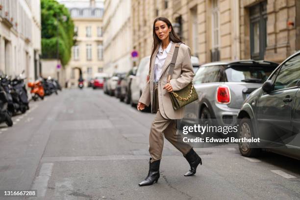 Tamara Kalinic wears gold earrings, a gold chain pendant necklace, a Saint Laurent white shirt, a beige oversized Y/Project blazer jacket, a shiny...