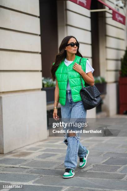 Tamara Kalinic wears black sunglasses, gold earrings, a gold chain pendant necklace, a black t-shirt, a white t-shirt with a slogan 'with me', a...