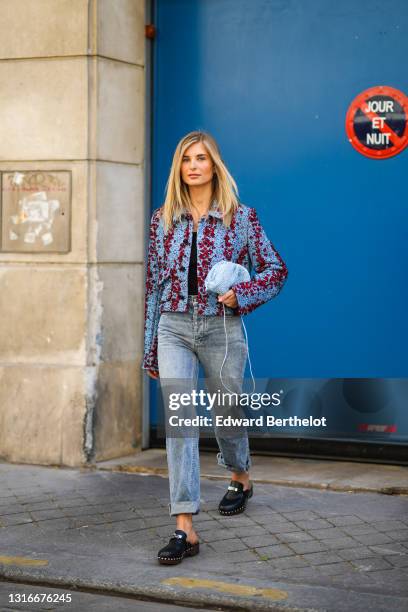 Xenia Adonts wears a black ribs t-shirt, a pale blue and red embroidery Bottega Veneta tweed jacket, blue faded denim ripped rolled-up boyfriend...
