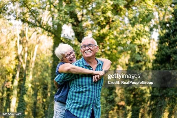 portrait of beautiful senior couple hugging and posing in the spring park - change purse stock pictures, royalty-free photos & images