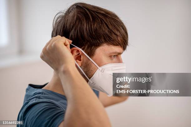 portrait of a young man put on a protective face mask ffp2 - griepmasker stockfoto's en -beelden