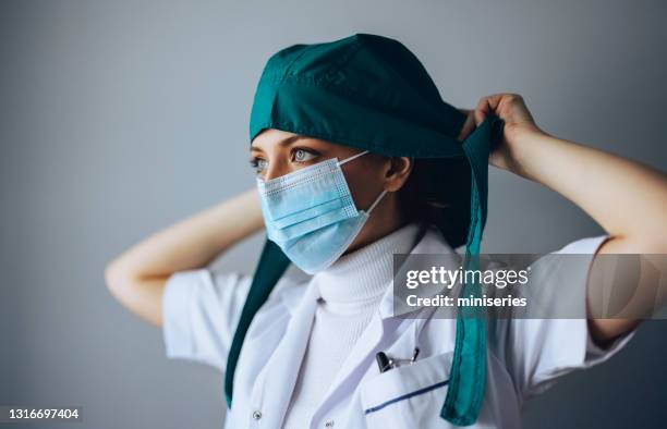 female surgeon putting on surgical cap in operating room - portrait studio shot stock pictures, royalty-free photos & images