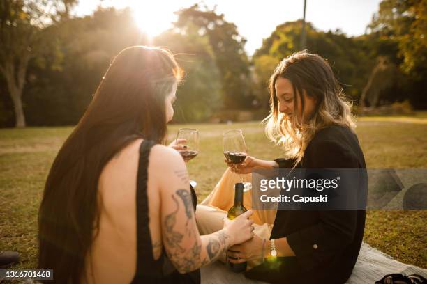 young female couple drinking wine at sunset - dia 2 stock pictures, royalty-free photos & images