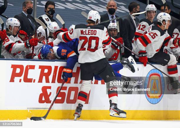 Michael McLeod of the New Jersey Devils checks Braydon Coburn of the New York Islanders into the Devils bench during the third period at the Nassau...