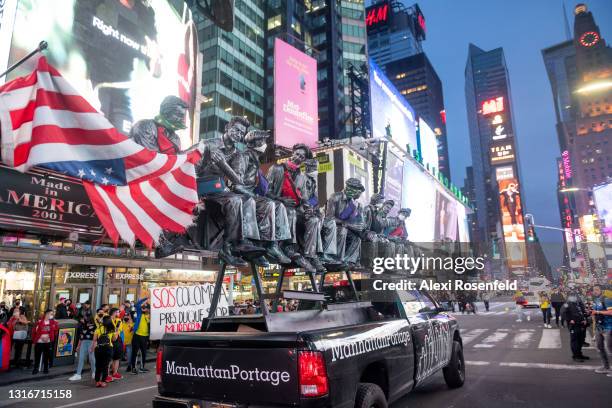 Truck advertising Manhattan Portage bags with a sculpture inspired by the Charles Clyde Ebbets photograph, 'Lunch Atop A Skyscraper' rides through...