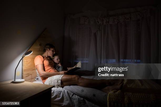 madre leyendo a su hija en la cama por la noche - bedtime fotografías e imágenes de stock