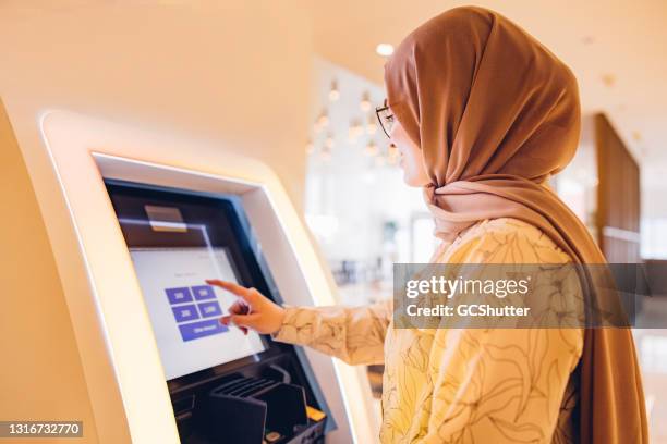 chica de oriente medio usando cajero automático para retirar el dinero - bank holiday fotografías e imágenes de stock