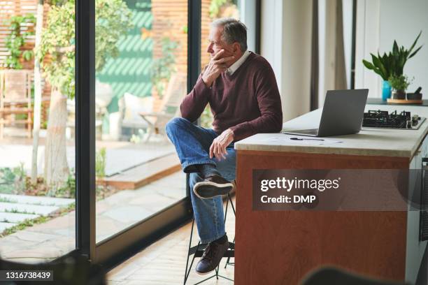 ontsproten van een hogere mens die alleen in zijn keuken zit en beklemtoond na het berekenen van zijn financiën thuis kijkt - erfenis stockfoto's en -beelden